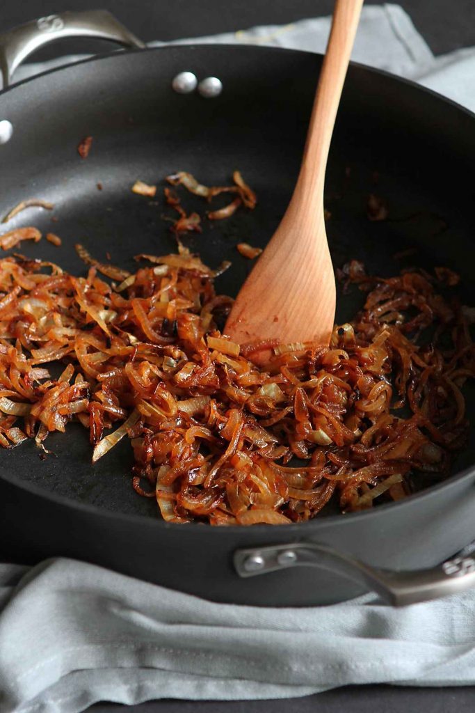 Caramelized onion and a wooden spatula in a large nonstick skillet